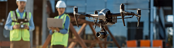 Several people on a job site using a drone to survey the field. 