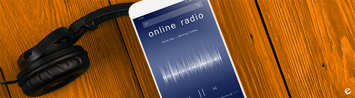 A mobile phone with a live online radio stream playing and headphones.