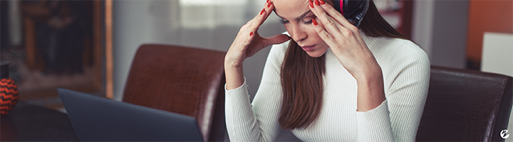 A woman in front of her laptop with an expression of frustration.