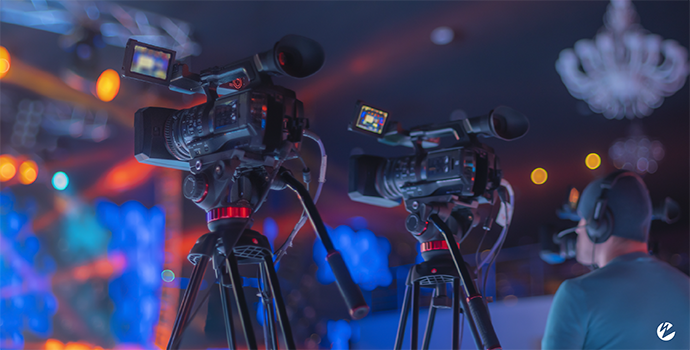 A video production team live streaming a festival by capturing the live event on camera.