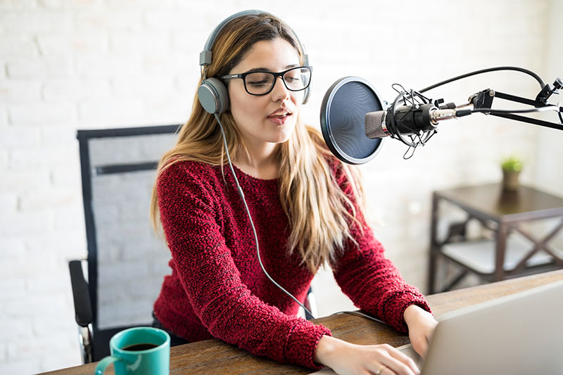 A woman radio host wearing headphones and broadcasting a live stream audio-only.