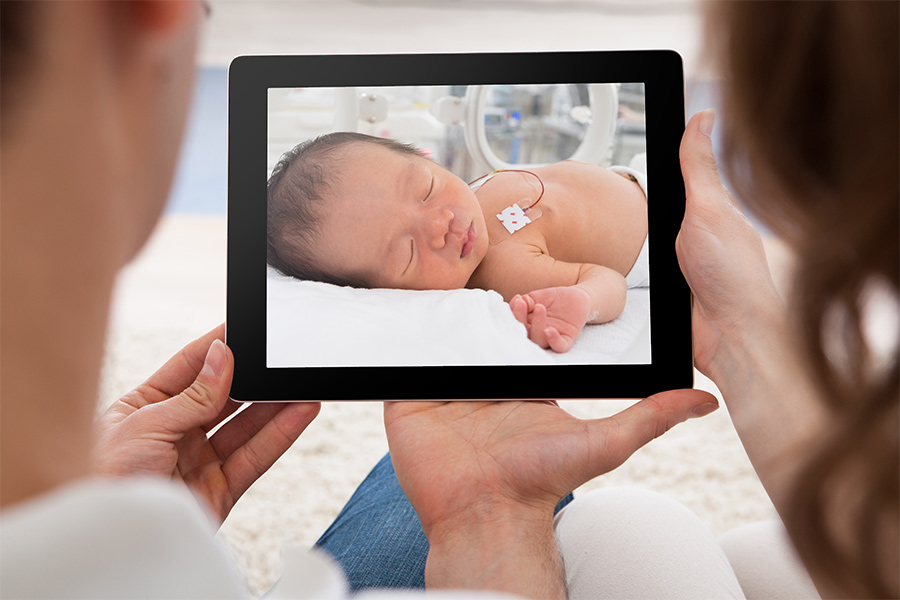 Parents viewing video stream of neonate in hospital