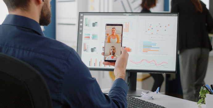 Corporate worker holding smartphone for video call conversation with colleagues about project planning and development. Man using mobile phone to talk to partners on online conference