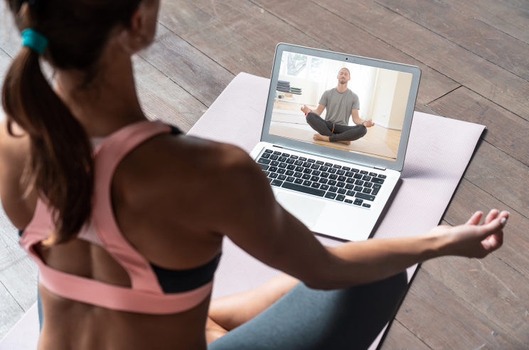 Woman in front of laptop watching yoga live stream